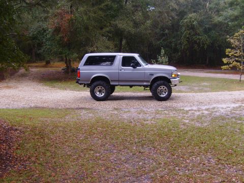 1995 Ford Bronco - Lifted 1995 Ford Bronco with aftermarket wheels and tires sits on a gravel lot.