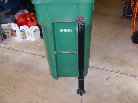 1995 Ford Bronco - A drive shaft is attached to a green trash can, which has a number printed on its side.