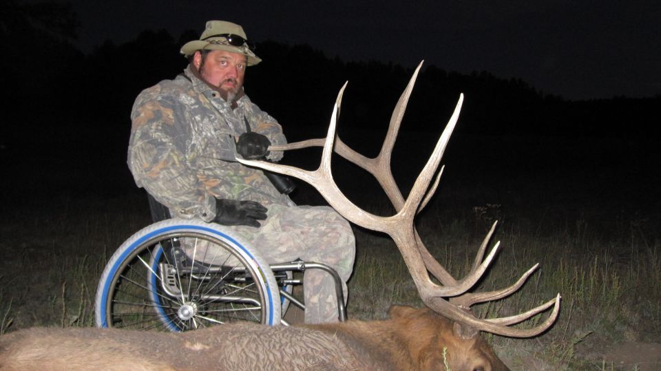 Man in wheelchair next to large elk antlers