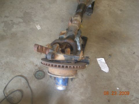 1991 Ford F-150 - A rusty front axle assembly with a brake rotor and blue hub is shown on a concrete floor.