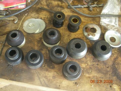 1991 Ford F-150 - Various vehicle suspension bushings and washers are laid out on a wooden surface, possibly for replacement or repair.