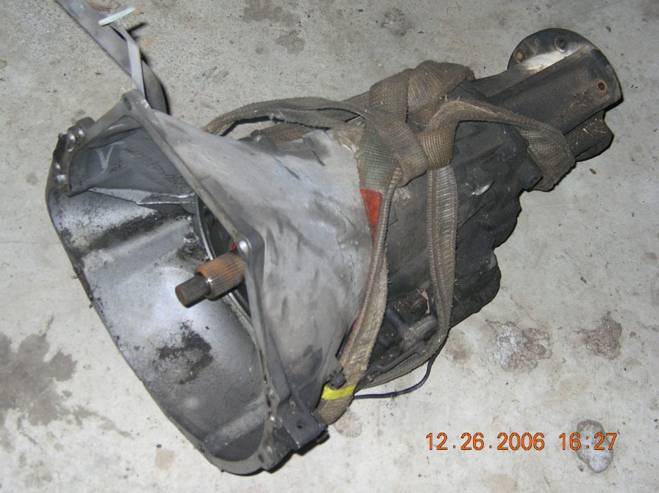 Transmission assembly with straps, resting on concrete floor. Date stamp shows 12.26.2006