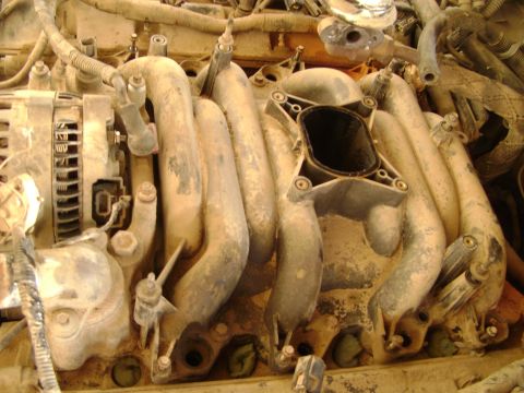 1998 Ford Crown Victoria - Close-up view of a dusty engine intake manifold and alternator assembly.
