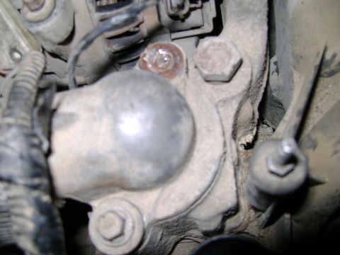 1998 Ford Crown Victoria - A close-up view of a dirty engine component, showing bolts and wiring details.