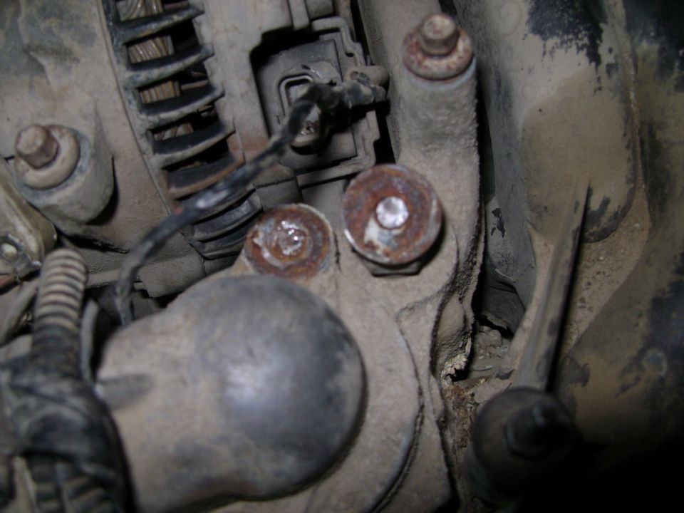 Close-up of engine part with rusty bolts and wiring
