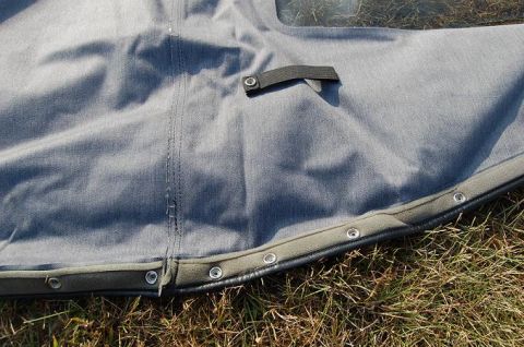 1994 Ford Bronco - Close-up of a gray soft top with visible snaps and a fabric strap, resting on grass.