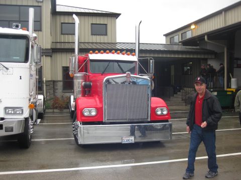 1981 Kenworth W900A - A man walks past a red 1981 Kenworth W900A truck parked outside a building.