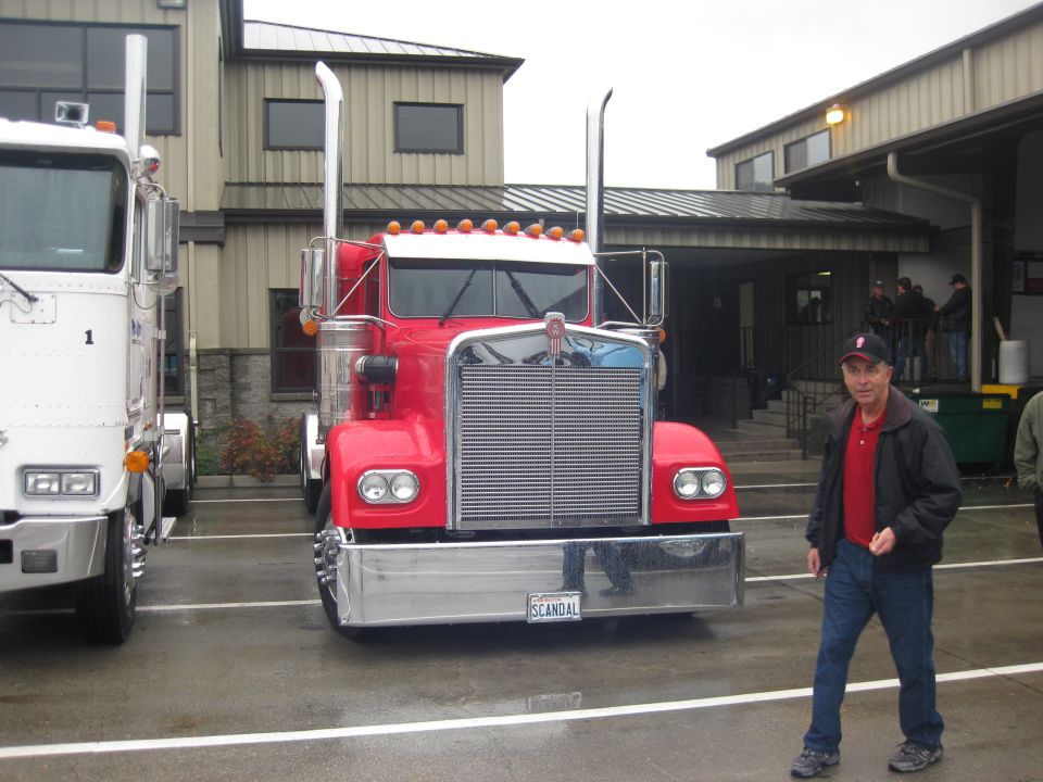 Red 1981 Kenworth W900A truck with chrome grille and bumper, parked next to a white truck