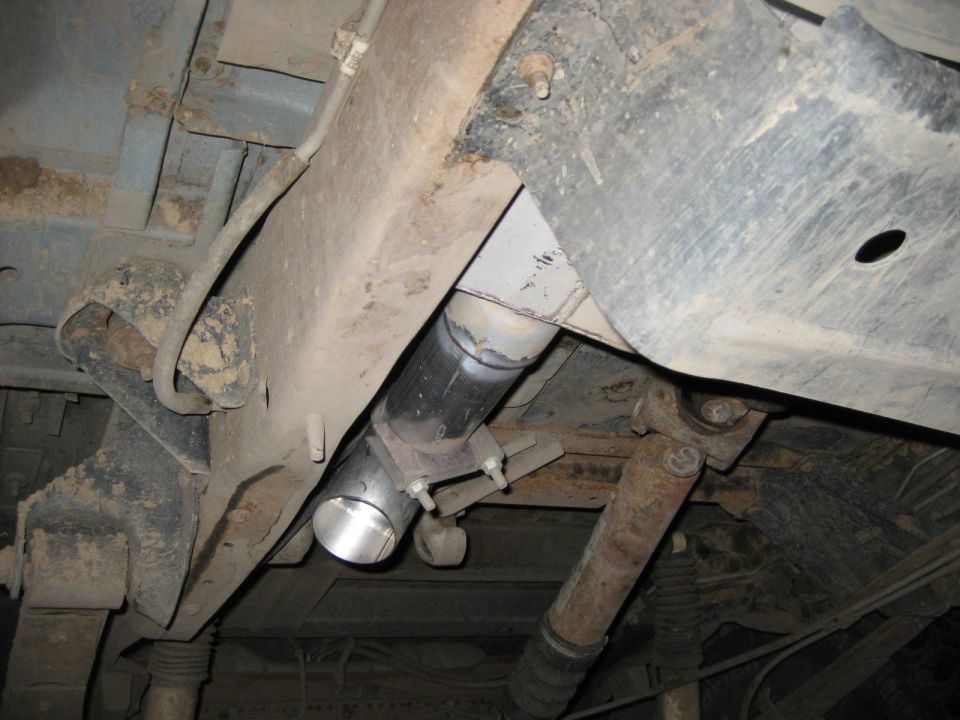 Underside of a vehicle showing a custom exhaust pipe section being installed