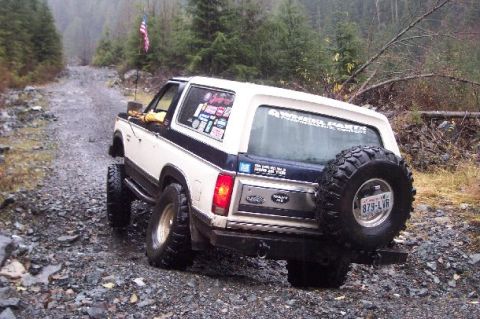1982 Ford Bronco - This 1982 Ford Bronco is navigating a rough, unpaved road in a forested area.