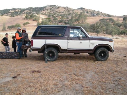 1982 Ford Bronco - Ford Bronco parked in a rural landscape with people and hunting equipment nearby.