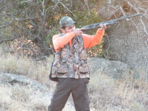 1982 Ford Bronco - Hunter aims a shotgun in a wooded outdoor setting.