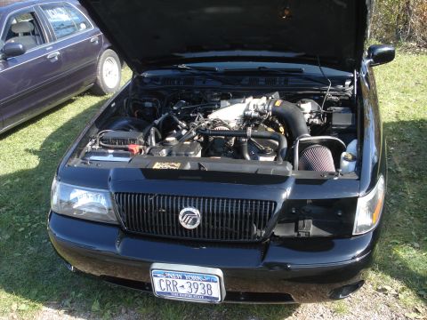 2000 Ford Crown Victoria - A black Mercury Grand Marquis is shown with its hood open, revealing the engine bay and a New York license plate.
