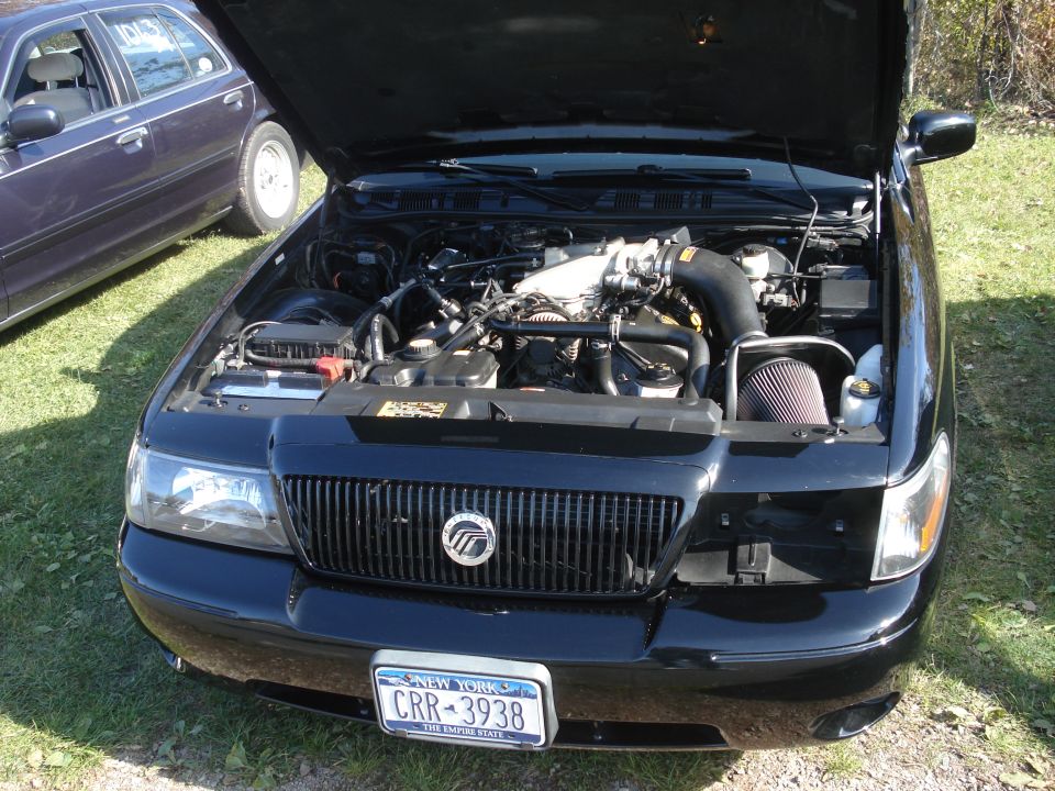 Black Mercury Grand Marquis with hood open, showing engine and New York license plate CRR-3938