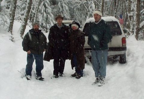 1982 Ford Bronco - Four people pose in a snowy forest next to a white SUV.