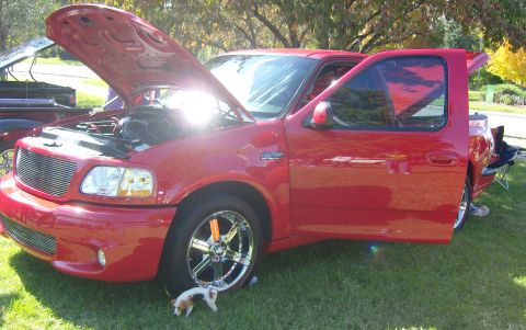 2007 Ford Mustang - Red pickup truck with hood and driver door open, displaying its engine and chrome wheels.