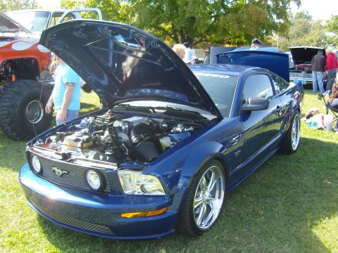 2007 Ford Mustang - A blue Ford Mustang is displayed with its hood open at an outdoor event.