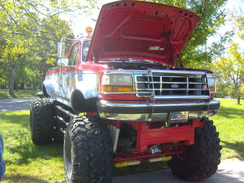 2007 Ford Mustang - This lifted pickup truck features a red and chrome exterior with a prominent American flag license plate and its hood open.