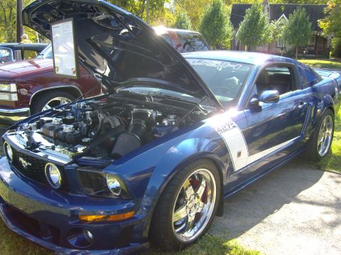 2007 Ford Mustang - A blue 2007 Ford Mustang 427 is displayed with its hood open, revealing the engine bay and a prominent side stripe.