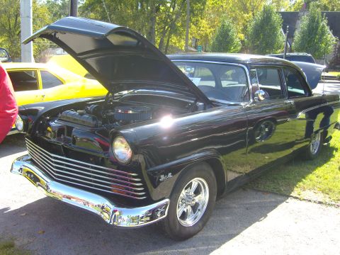 2007 Ford Mustang - Black sedan from 1955 on display with its hood open, showing the engine bay.