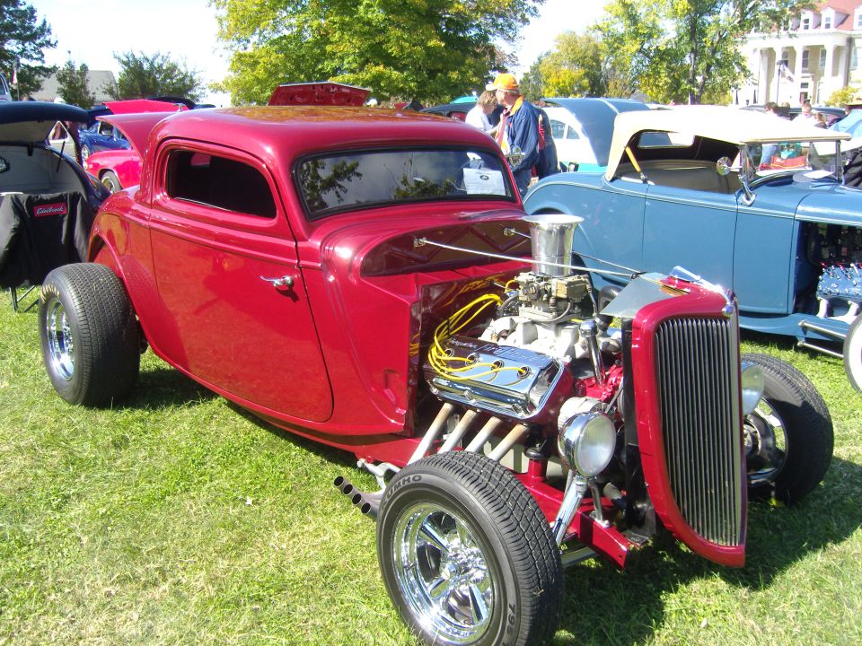 Red hot rod with exposed V8 engine and chrome grille