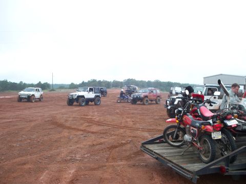 1995 Ford Bronco - Several off-road vehicles and motorcycles are gathered in a dirt lot.