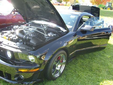 2007 Ford Mustang - A black 2007 Ford Mustang is parked on grass with its hood and door open, revealing the engine and interior.