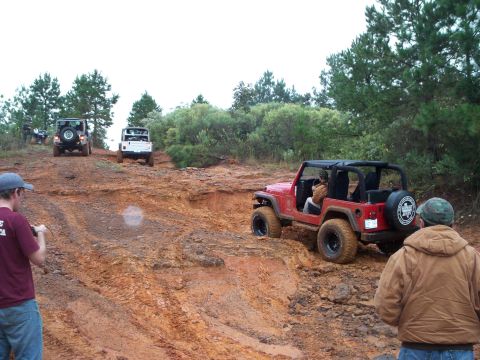 1995 Ford Bronco - Multiple Jeeps navigate a challenging muddy trail during an off-road excursion.
