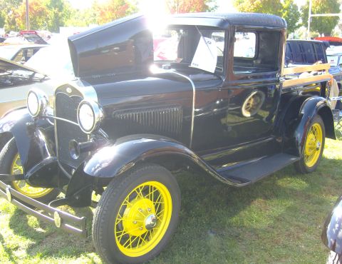 2007 Ford Mustang - A classic black Ford Model A pickup truck with bright yellow wheels is displayed outdoors.
