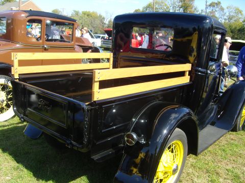 2007 Ford Mustang - A vintage black Ford pickup truck with a wooden bed and yellow wheels is parked on grass.