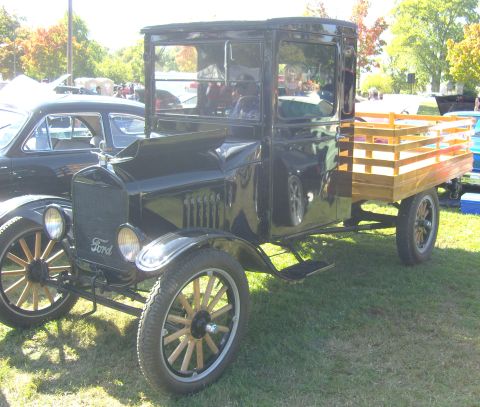 2007 Ford Mustang - A black Ford Model T truck is parked on a grassy field next to another vehicle.