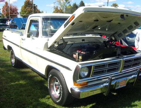 2007 Ford Mustang - White Ford pickup truck with hood open, parked on grass at an outdoor event.
