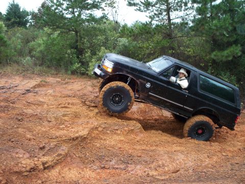 1995 Ford Bronco - This 1995 Ford Bronco is navigating a challenging off-road course with steep inclines and muddy terrain.