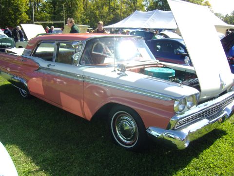 2007 Ford Mustang - A classic two-tone pink and white sedan is displayed with its hood open at an outdoor car show.