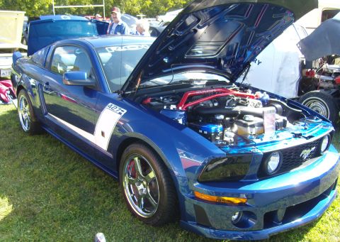 2007 Ford Mustang - A blue Ford Mustang with its hood open, displaying the engine and custom racing stripes.