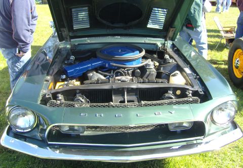 2007 Ford Mustang - The front of a green 1967 Shelby GT500 is visible with the hood open, revealing the engine compartment.