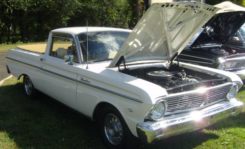 2007 Ford Mustang - A white Ford Ranchero pickup truck is displayed with its hood open, parked next to another vehicle.