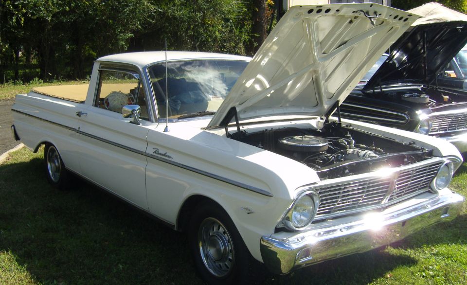White Ranchero pickup truck with hood open, parked next to a black car