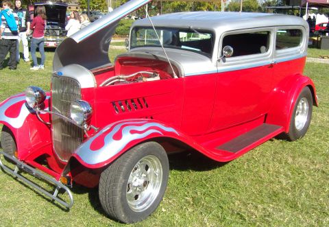 2007 Ford Mustang - A classic red and silver sedan hot rod with flame decals is displayed outdoors.