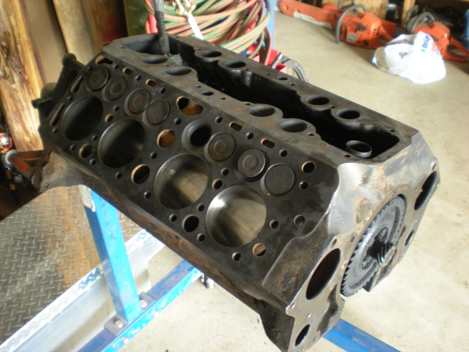 Engine block on a blue stand, showing cylinder heads and valves. Gears are visible on the side