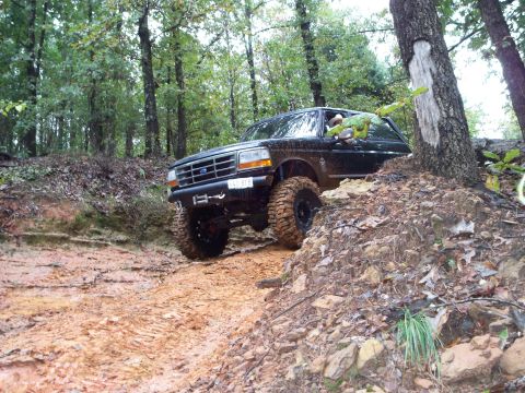 1995 Ford Bronco - This 1995 Ford Bronco navigates a challenging muddy path through a wooded area.