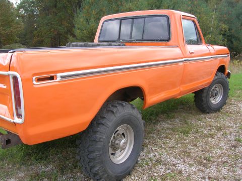 1975 Ford F-250 - This lifted pickup truck is shown from the rear quarter, with a focus on its large off-road tires and bright orange paint.