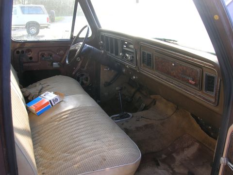 1975 Ford F-250 - The interior of a 1975 Ford F-250 shows wear and tear, with a pack of cigarettes on the seat.