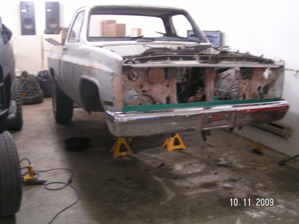 Stripped square-body Chevy pickup on jack stands with front sheet metal removed, 2009