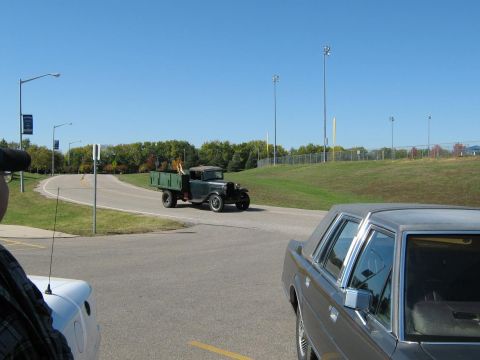 2000 Mercury Grand Marquis - A vintage green truck is seen driving on a road, with a modern car partially visible in the foreground.