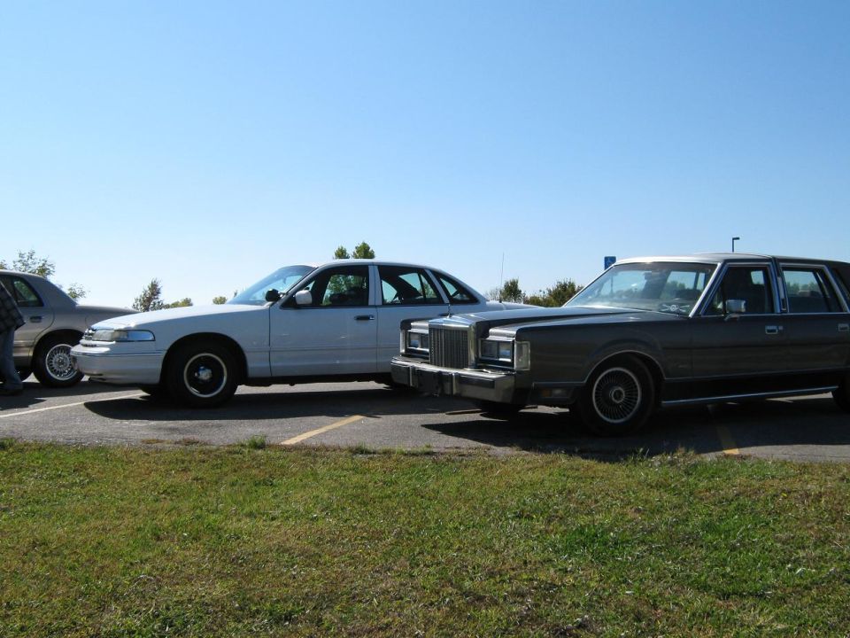 White sedan and a dark sedan parked next to each other