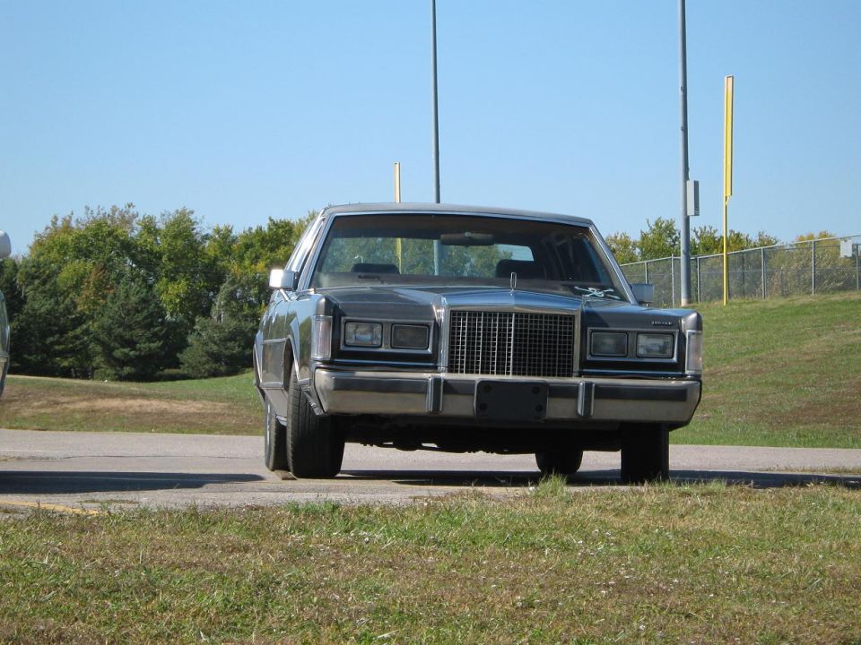 Front view of a dark sedan with a prominent chrome grille and square headlights