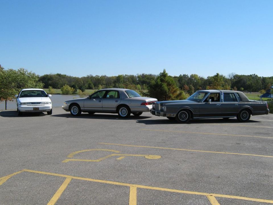 Three sedans parked side-by-side, a white sedan, a silver sedan, and a dark gray sedan