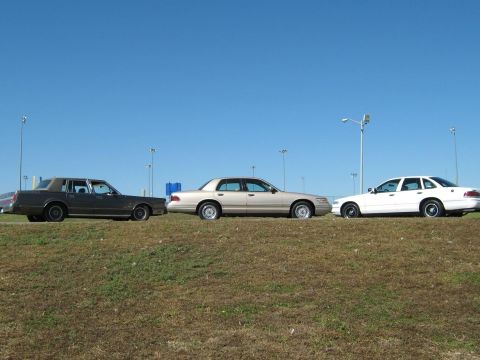 2000 Mercury Grand Marquis - Three sedans, including a 2000 Mercury Grand Marquis, are parked side-by-side on a grassy area.
