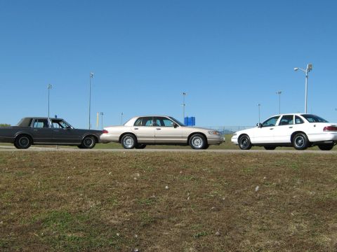 2000 Mercury Grand Marquis - Three sedans are lined up on the side of the road, with the middle vehicle identified as a 2000 Mercury Grand Marquis.